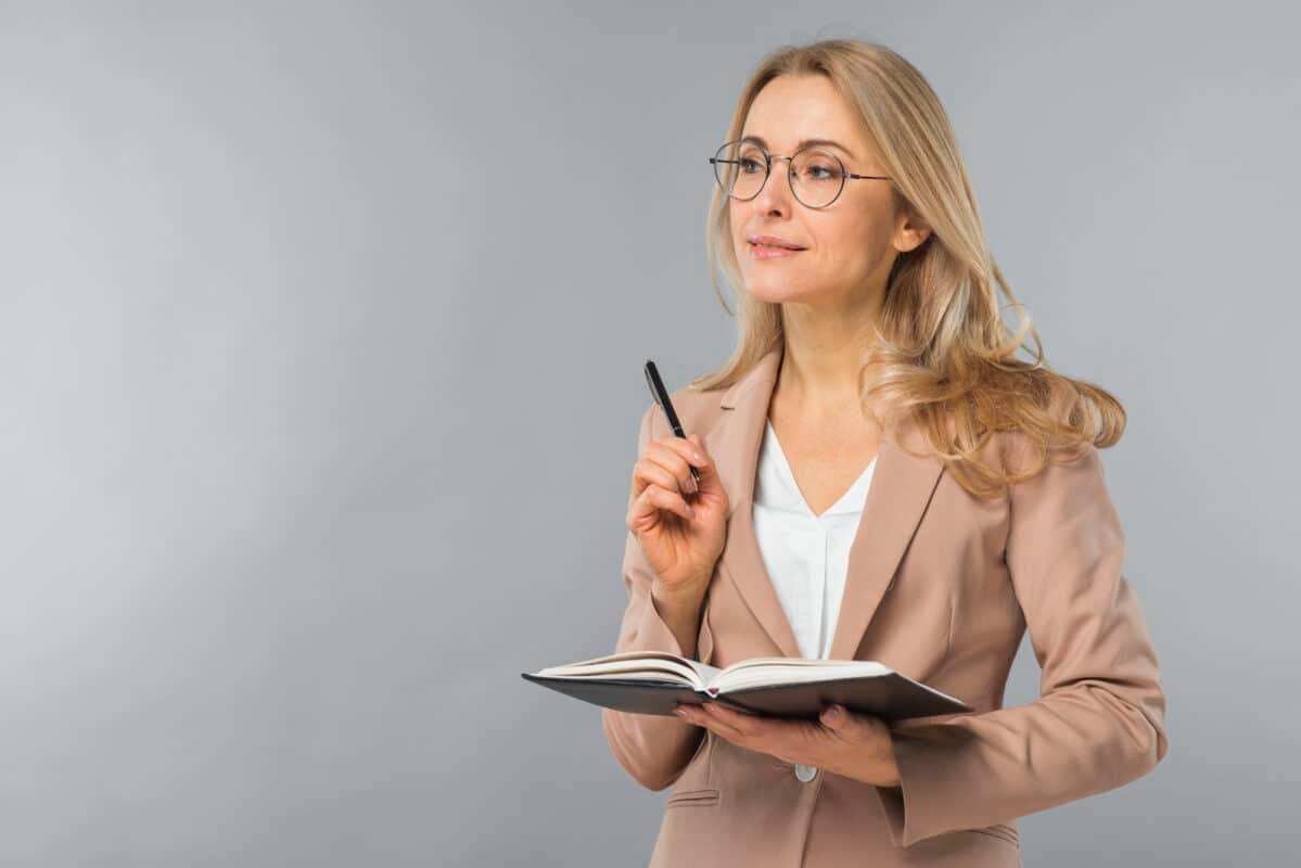 A confident and smiling professional female tutor holding a pen and diary, representing O-Level and academic coaching in Karachi.